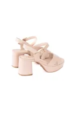 Sandalias de cuero color crema, con plataforma y taco ancho. Presentan tiras cruzadas sobre el empeine y pulsera con hebilla al tobillo.