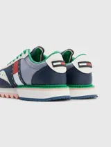 Zapatillas Tommy Jeans de cuero sintético color azul marino, gris y blanco, con cordones verdes y suela gruesa dentada en rosa y blanco.