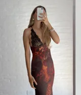 Vestido largo de microtul con estampado abstracto en tonos marrones, azules y naranjas. Tiene escote en V con encaje negro y breteles finos.