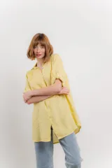 Camisa amarilla de lino con corte recto y calce suelto. Tiene cuello camisero, botones en el frente y mangas cortas con presilla y botón.
