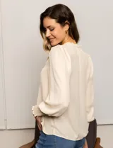Blusa color beige de gasa con escote en V, apliques de botones y detalle de punto smock en hombro y puño.