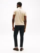 Chomba color beige con tejido jacquard, cuello tipo chomba, billetera de dos botones, logo de Tommy Hilfiger bordado en la manga y corte regular.