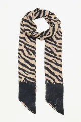 Bufanda larga de poliéster color crema con estampado animal print de cebra en tonos negro y marrón. Tiene lentejuelas negras aplicadas en los extremos.