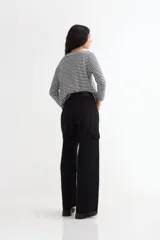 Pantalón de jean negro, tiro alto, de corte ancho y largo completo, con bolsillos cargo a los costados de las piernas.