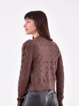 Cárdigan tejido de punto color gris con diseño trenzado, escote en V y cierre frontal con botones marrones.