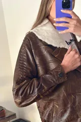 Campera bomber de cuero marrón veteado con cuello desmontable de corderito crudo y detalle de pasamanería en las mangas.