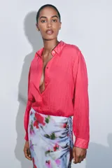 Camisa color fucsia con textura de rayas tejidas, de cuello solapa y manga larga. Cierre frontal con botones.