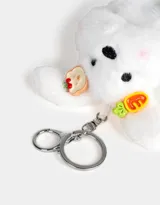 Llavero de peluche blanco con forma de conejo, con accesorios en las orejas y mosquetón metálico para colgar.