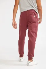 Pantalón deportivo de invierno color burdeos, con fit regular y puños en los tobillos, confeccionado en frisa y bolsillos con cierre.