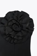Top palabra de honor negro con detalle de flor con volumen en el mismo tejido. Cierre con cremallera oculta en la costura.