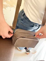 Bandolera color visón, fabricada en cuero con forro de tela. Tiene bolsillo interior y exterior. Entra billetera grande.