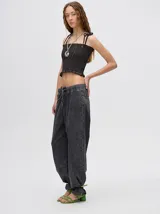 Top corto negro con textura fruncida, tirantes finos con lazos ajustables y corte crop.