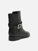 Bota corta negra de cuero con hebilla metálica plateada.