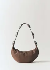 Bolso marrón de cuero con asa de hombro y tachuelas decorativas plateadas.
