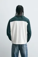 Camiseta de manga larga con cuello redondo, diseño color block en blanco y verde oscuro, con el número 80 y la inscripción 'Saint Frederic' bordados en el frente.