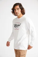 Remera de manga larga blanca para hombre con logo estampado en el frente y cuello redondo.