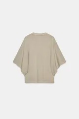 Camiseta blanca de manga corta con corte oversize y cuello redondo. El diseño presenta mangas amplias tipo capa que caen desde el hombro.