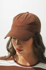 Gorra marrón con logo circular bordado en rojo en el frente.