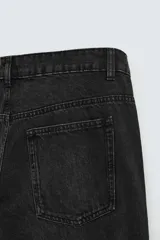Pantalón de denim color beige, corte relaxed fit, con bolsillos laterales tipo cargo con solapa y cierre de botón. Cierre frontal con botón y cremallera.
