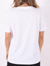 Remera blanca con estampado gráfico en tonos lilas y verdes, de corte clásico.