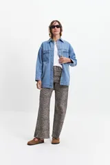 Campera de jean celeste de corte holgado, con cuello camisero, cierre frontal con botones metálicos, mangas largas con puños abotonados, bolsillos frontales con solapa y costuras a la vista.