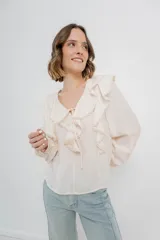 Blusa color crema con volados en el frente, detalle de puntilla y bordados florales en mangas.