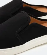 Championes mule de lona negra con puntera redonda y suela blanca.
