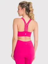 Top deportivo fucsia con soporte medio, almohadillas removibles, tirantes finos con detalle de encaje y espalda con tirante grueso central.