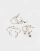 Set de tres pares de aros tipo argolla bañados en plata, con dijes colgantes: luna creciente, estrella de ocho puntas y strass.