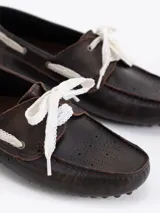 Mocasín Lyon de cuero vacuno color rosado con efecto gastado. Presenta detalles de picado en los laterales y la capellada, y se ajusta con cordones de encaje blancos. Suela de goma.