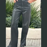 Pantalón de cuero negro de tiro medio y pierna recta con tajo en el ruedo.