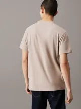 Remera color beige de algodón, con cuello redondo y mangas cortas. Cinta lateral con logo de la marca.