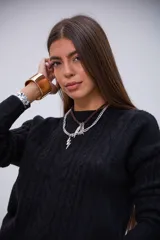 Sweater negro de punto con diseño de ochos, cuello redondo y mangas largas.