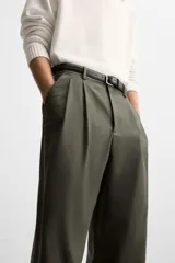 Pantalón verde oliva de corte amplio con pliegues en la parte delantera, bolsillos laterales y traseros de ojal.