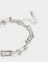Pulsera plateada con eslabones tipo clip y esferas.