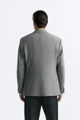 Blazer straight fit color gris claro confeccionado en tejido con viscosa. Tiene cuello con solapas de muesca, manga larga acabada en puño con botón, bolsillo de vivo en pecho, bolsillos de plastrón en cadera y bajo con aberturas en espalda. Cierre frontal de botonadura.