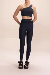Top deportivo negro con escote asimétrico de un solo hombro y recortes laterales. Cuenta con copas removibles y está confeccionado en tejido aterciopelado con tacto suave tipo algodón.