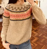 Sweater tejido de mohair color beige con cuello redondo y diseño con motivos geométricos en el canesú en tonos marrón, naranja y azul.