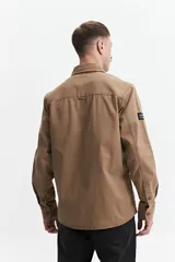 Sobrecamisa color marrón claro de twill de algodón, con cuello clásico, cierre frontal con botones a tono, dos bolsillos de parche con solapa abotonada en el pecho y mangas largas con puños abotonados.