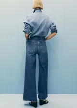 Pantalón de jean azul de tiro alto, corte wide leg, con bolsillos delanteros y traseros, cierre con cremallera y botón.
