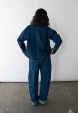 Conjunto de jean azul marino oscuro, compuesto por una chaqueta de corte holgado y un pantalón de tiro medio-bajo con corte vertical.