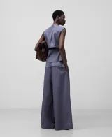 Pantalón ancho color gris azulado, de lino y algodón, con pinzas delanteras, canesú en delantero y espalda en tejido a contraste, cinturilla elástica en espalda y bolsillos laterales.