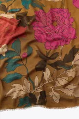 Pañuelo rectangular color marrón con estampado de flores rosas, hojas verdes y detalles en beige. Tiene terminaciones deshilachadas.