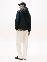 Campera con capucha de poliéster reciclado, color azul marino, con cierre frontal de cremallera. Presenta detalles en los colores de la marca (RWB) y un logo engomado de Tommy Hilfiger en la manga.