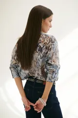 Camisa celeste con estampado abstracto en tonos marrones y azules, de corte clásico, cuello camisero y mangas largas con puños abotonados.
