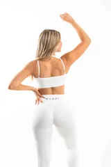 Conjunto deportivo blanco compuesto por un top con escote halter y calzas largas de tiro alto con bolsillos laterales.