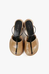 Mule color caramelo con plataforma y taco cilíndrico, tira superior negra y puntera cuadrada.