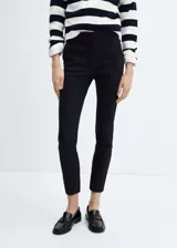 Pantalón negro de corte skinny y largo capri, con tiro medio, bolsillos laterales y traseros de ribete.
