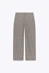 Pantalón de tiro alto con estampado de cuadros en tonos marrones y grises, con bolsillos delanteros y falsos bolsillos traseros. Cierre frontal con cremallera y botón.