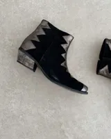 Botín de cuero vacuno color bronce con puntera y caña en cuero negro. Diseño con borde superior en zigzag y taco de madera.